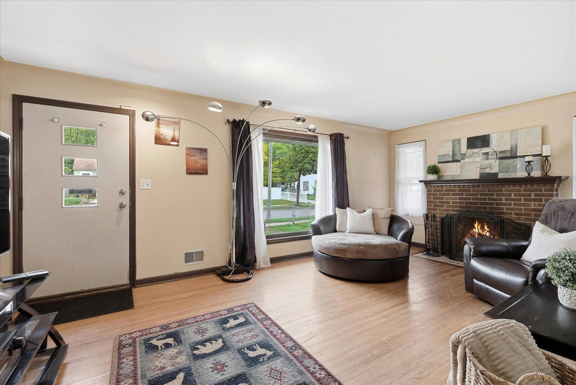 4840 N 6th Street, 41, Minneapolis, MN 55430 Spacious main-level living room featuring hardwood floors, a large picture window that fills the space with natural light, and a classic brick wood-burning fireplace.