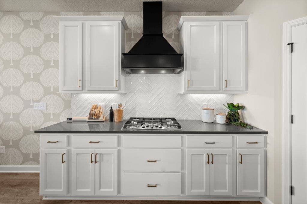 The Gourmet Kitchen features a beautiful Wood hood fan, beautiful cabinetry and a gorgeous herringbone pattern backsplash.  5 burners on that gas cooktop!