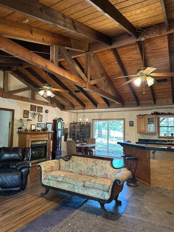 11420 County Road 420, Tyler, TX 75704 Living room featuring ceiling fan with notable chandelier, wooden ceiling, concrete flooring, and lofted ceiling with beams