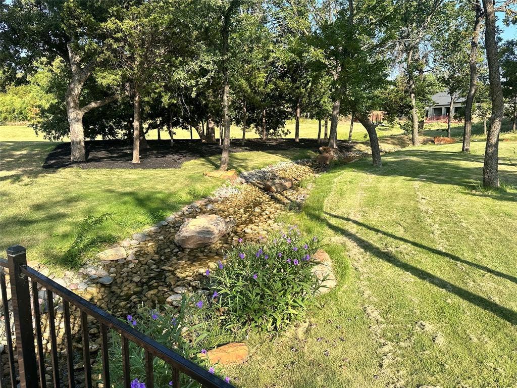 124 Park Avenue, Keller, TX 76262 Expansive lawn with mature trees, a creek bed featuring natural stone accents, and ornamental plantings