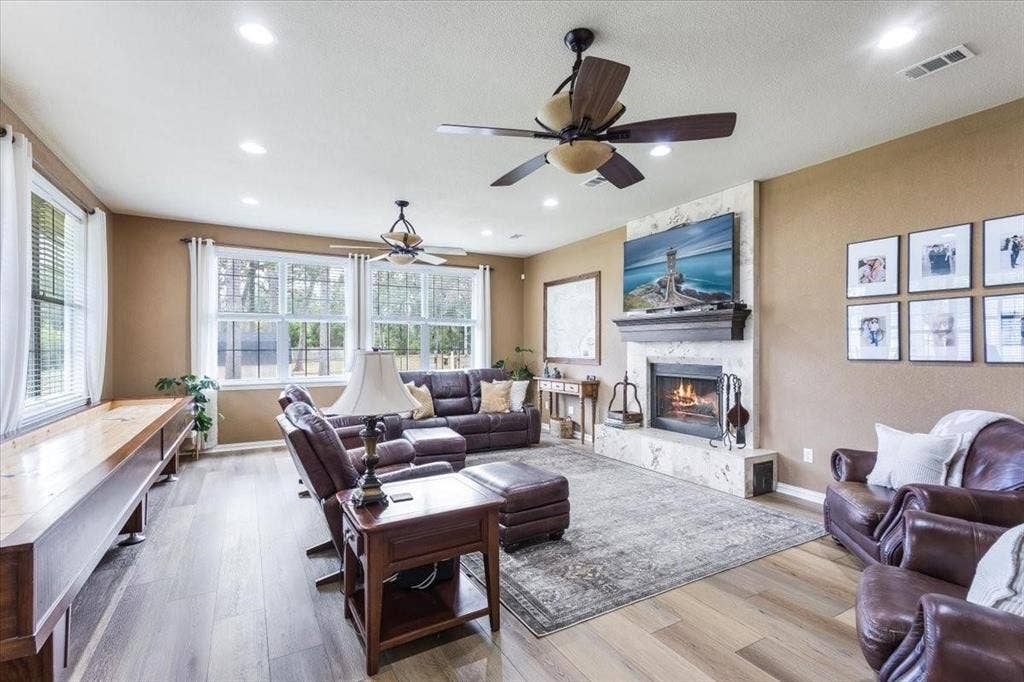 Living area featuring a large fireplace, baseboards, visible vents, and wood finished floors
