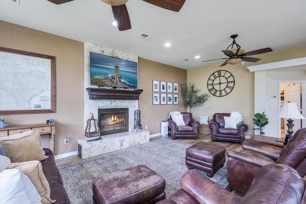Living area featuring a ceiling fan, a high end fireplace, visible vents, and wood finished floors