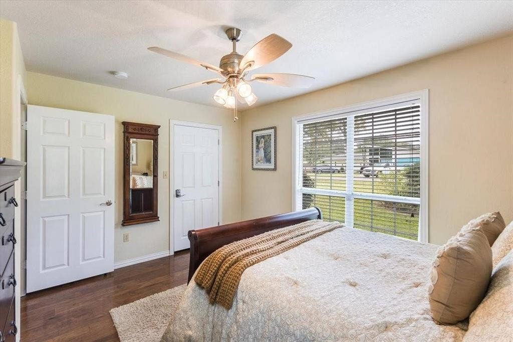 Bedroom with dark wood-type flooring, ceiling fan, and baseboards