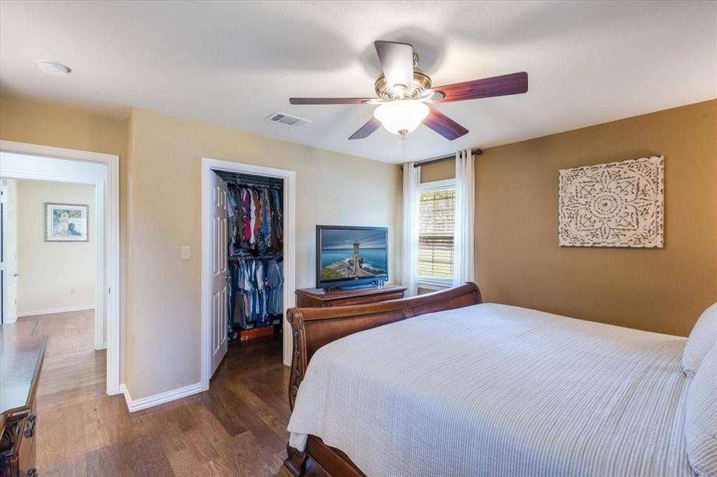 Bedroom featuring baseboards, visible vents, wood finished floors, a spacious closet, and a closet