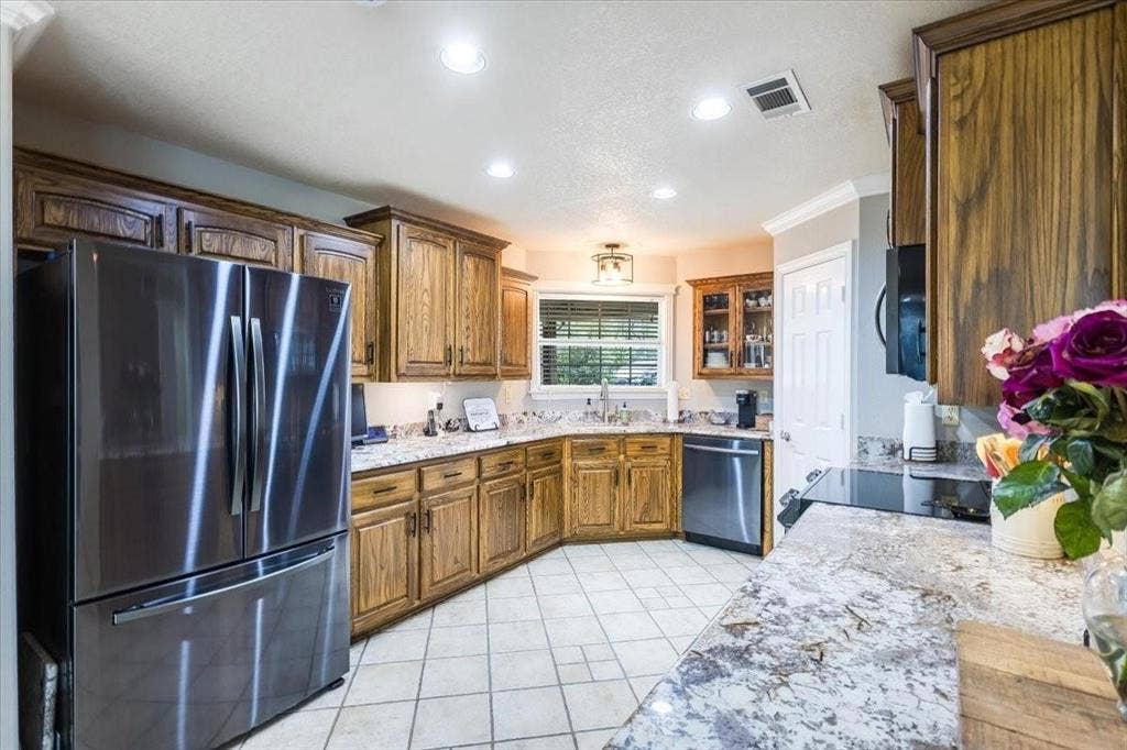 Kitchen featuring appliances with stainless steel finishes, brown cabinetry, visible vents, and a sink