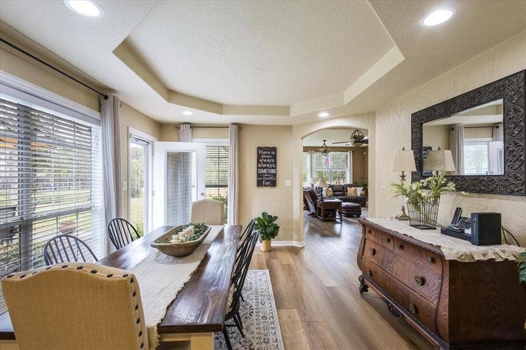 Dining room with a tray ceiling, arched walkways, and wood finished floors