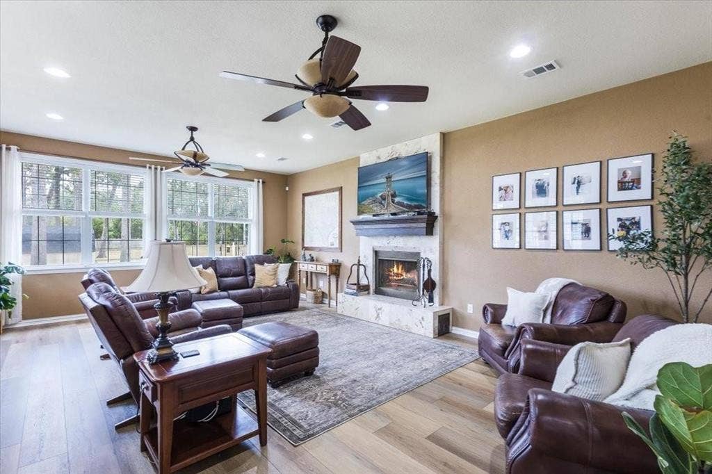 Living room featuring recessed lighting, visible vents, light wood-style floors, a stone fireplace, and baseboards