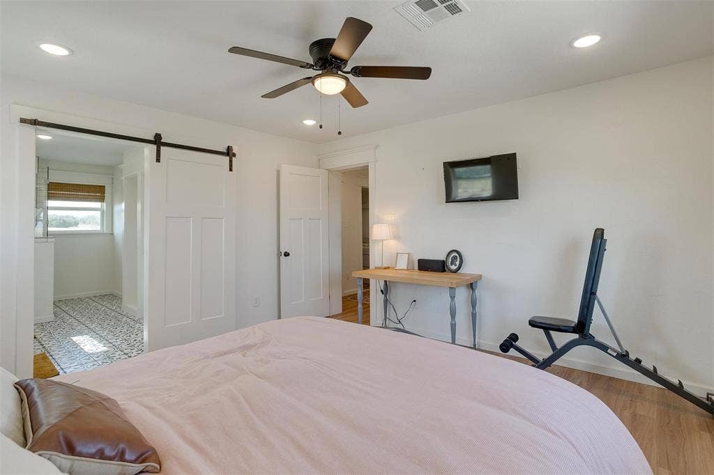 939 Twin Bends Road, Crawford, TX 76638 Bedroom with visible vents, baseboards, a barn door, recessed lighting, and wood finished floors
