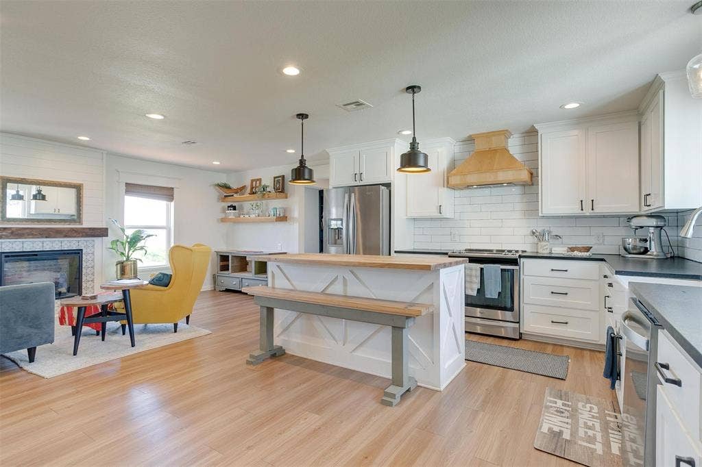 939 Twin Bends Road, Crawford, TX 76638 Kitchen with visible vents, light wood finished floors, custom exhaust hood, stainless steel appliances, and white cabinetry