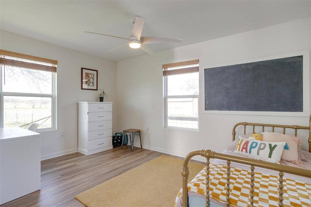 939 Twin Bends Road, Crawford, TX 76638 Bedroom featuring baseboards, multiple windows, and wood finished floors