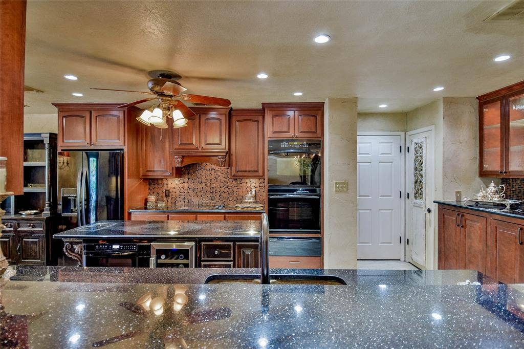 4009 Scenic Way, Granbury, TX 76049 Kitchen featuring black appliances, a ceiling fan, dark stone countertops, beverage cooler, and backsplash