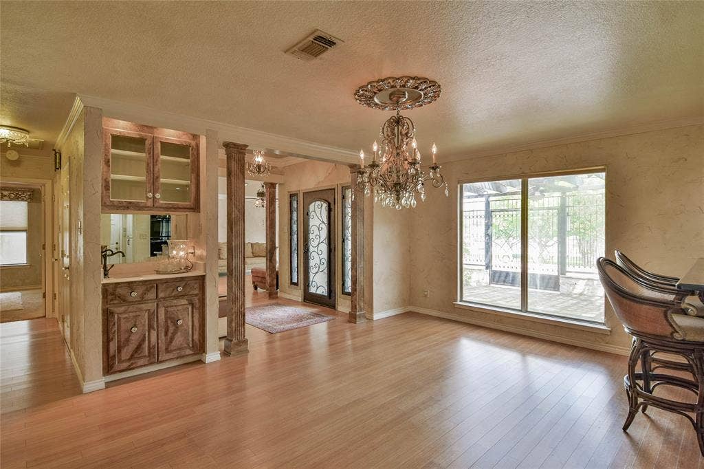 4009 Scenic Way, Granbury, TX 76049 Unfurnished dining area featuring crown molding, a chandelier, light wood-style flooring, a textured ceiling, and baseboards