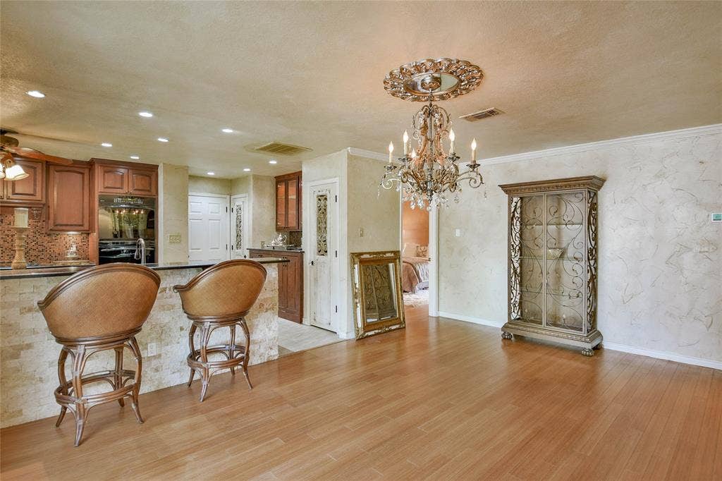4009 Scenic Way, Granbury, TX 76049 Kitchen with a chandelier, brown cabinets, light wood-type flooring, glass insert cabinets, and dark countertops