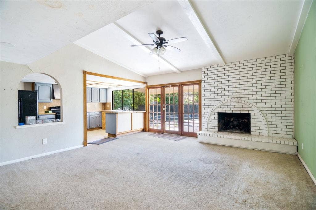 745 Oakland Street, Grand Prairie, TX 75052 Unfurnished living room with carpet flooring, a ceiling fan, baseboards, and a fireplace