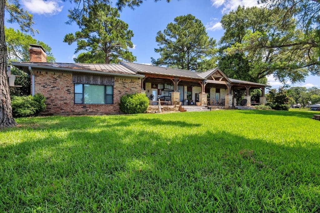 6903 Scott Street, Eustace, TX 75124 Back of property featuring a lawn, brick siding, a chimney, a standing seam roof, and covered porch