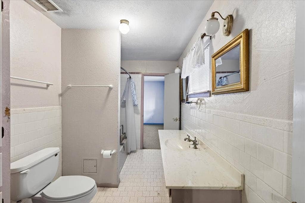 6903 Scott Street, Eustace, TX 75124 Bathroom featuring a shower with shower curtain, vanity, tile walls, tile patterned flooring, and a wainscoted wall