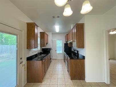 507 E Bryson Street, #A, Athens, TX 75751 Kitchen featuring dark countertops, brown cabinets, light tile patterned flooring, and a sink