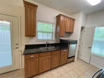 507 E Bryson Street, #A, Athens, TX 75751 Kitchen with a sink, dark countertops, stainless steel dishwasher, light tile patterned floors, and brown cabinets