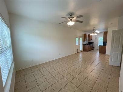 507 E Bryson Street, #A, Athens, TX 75751 Unfurnished living room featuring light tile patterned flooring, ceiling fan, and a chandelier