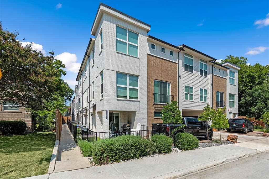 6319 Richmond Avenue, #107, Dallas, TX 75214 Multi-story townhouse exterior featuring a brick and siding facade, large grid windows, and a built-in covered parking area