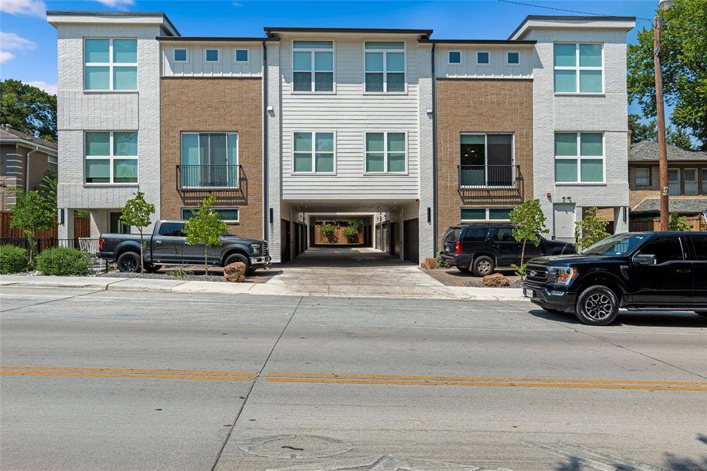 6319 Richmond Avenue, #107, Dallas, TX 75214 Multi-story exterior featuring a mix of brick and horizontal siding, oversized windows, private balconies with metal railings, and a covered ground-level drive-through