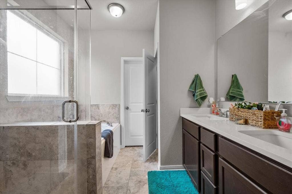 3501 Beutel Road, Waco, TX 76655 Full bathroom with double vanity, a stall shower, a garden tub, and tile patterned flooring