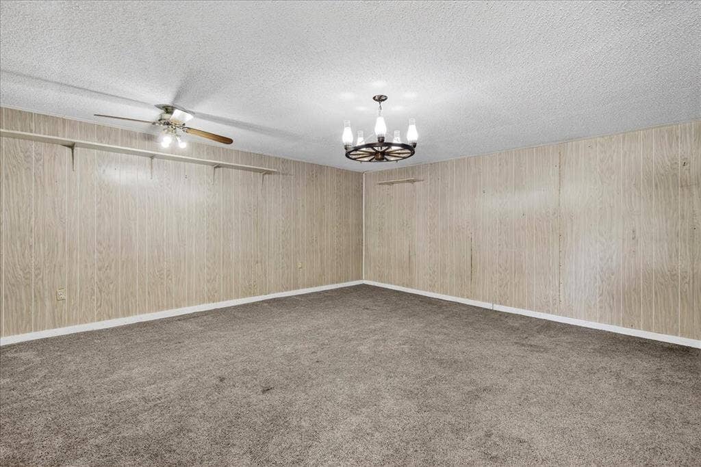 Unfurnished room featuring a chandelier, light carpet, a textured ceiling, and ceiling fan