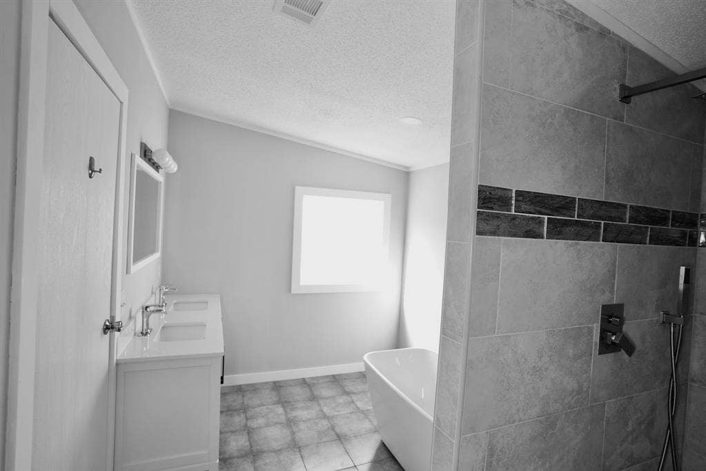 245 Oak Hill Court, Waxahachie, TX 75167 Bathroom with a freestanding tub, double vanity, a textured ceiling, and tiled shower