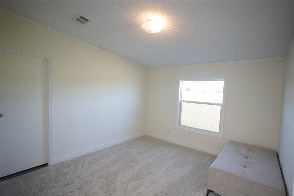 245 Oak Hill Court, Waxahachie, TX 75167 Unfurnished bedroom featuring light colored carpet, crown molding, and a textured ceiling