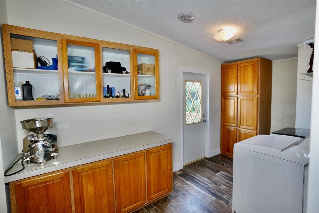 245 Oak Hill Court, Waxahachie, TX 75167 Washroom featuring dark wood finished floors, a textured ceiling, cabinet space, and crown molding
