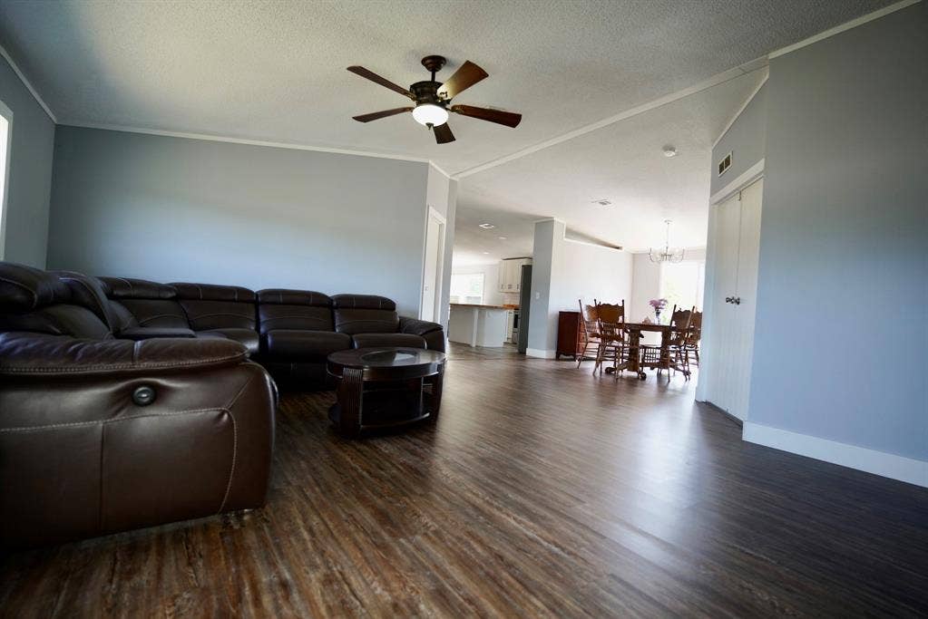 245 Oak Hill Court, Waxahachie, TX 75167 Living area with dark wood-style floors, a ceiling fan, a textured ceiling, a chandelier, and ornamental molding