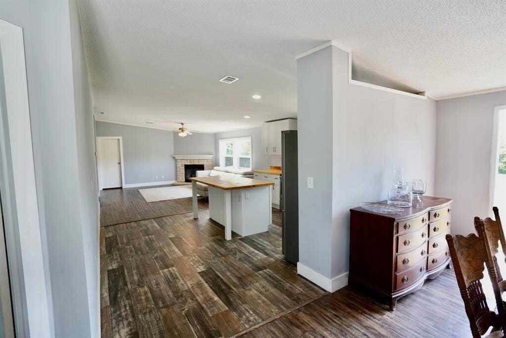 245 Oak Hill Court, Waxahachie, TX 75167 Kitchen with white cabinets, a brick fireplace, dark wood-style flooring, open floor plan, and crown molding