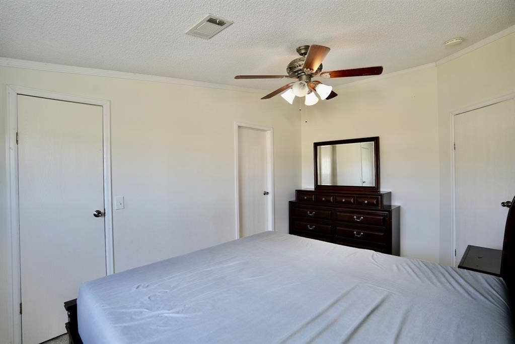 245 Oak Hill Court, Waxahachie, TX 75167 Bedroom featuring a textured ceiling, crown molding, and ceiling fan
