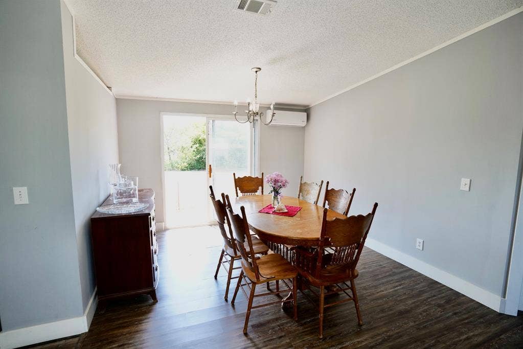 245 Oak Hill Court, Waxahachie, TX 75167 Dining area with dark wood finished floors, a chandelier, ornamental molding, a textured ceiling, and a wall mounted air conditioner
