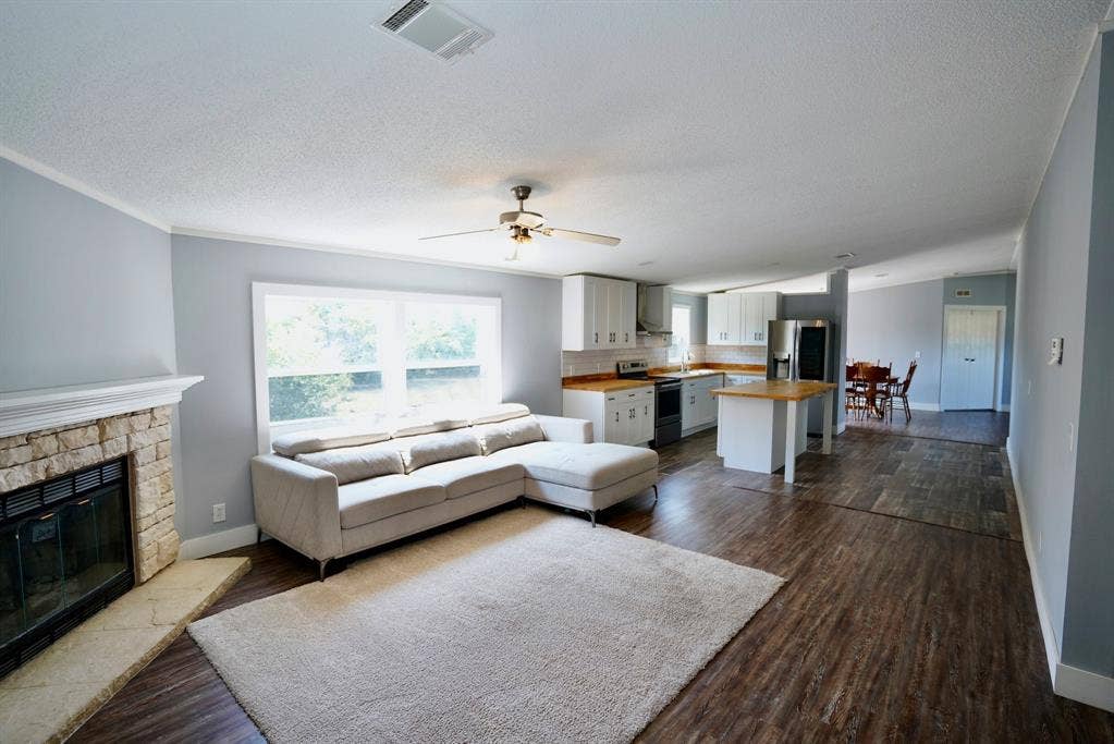 245 Oak Hill Court, Waxahachie, TX 75167 Living area with dark wood finished floors, a textured ceiling, a fireplace, and ceiling fan