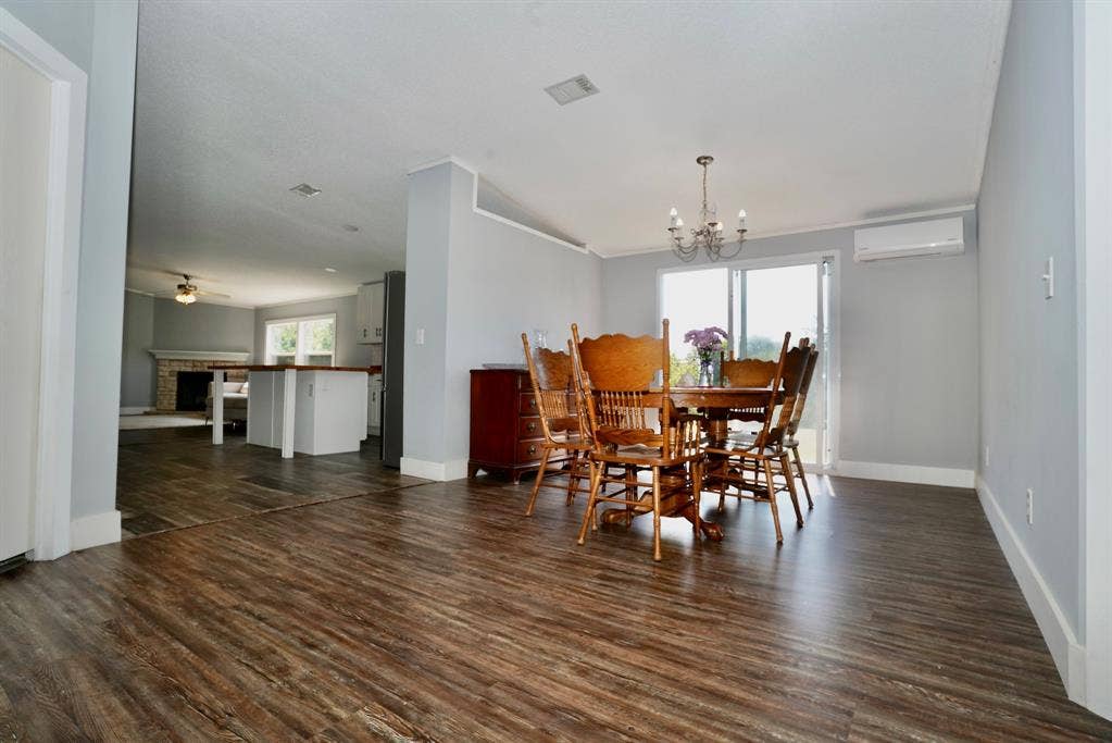 245 Oak Hill Court, Waxahachie, TX 75167 Dining area featuring dark wood-style floors, a brick fireplace, ceiling fan, a chandelier, and a wall mounted AC