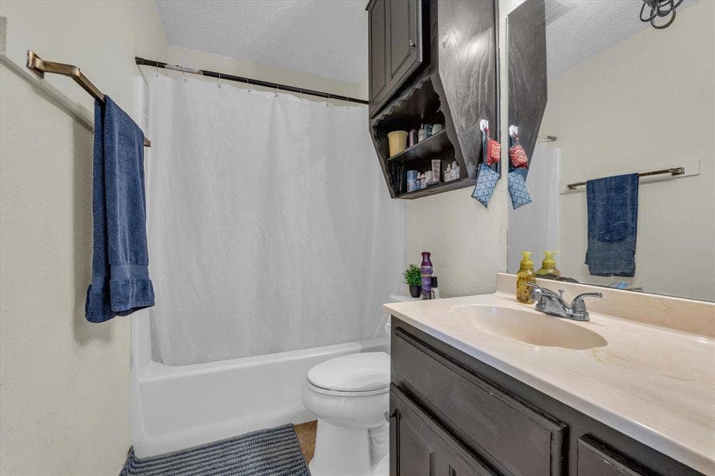 1349 S 11th Street, Waco, TX 76706 Full bathroom featuring vanity, shower / bath combination with curtain, a textured ceiling, and light tile patterned flooring