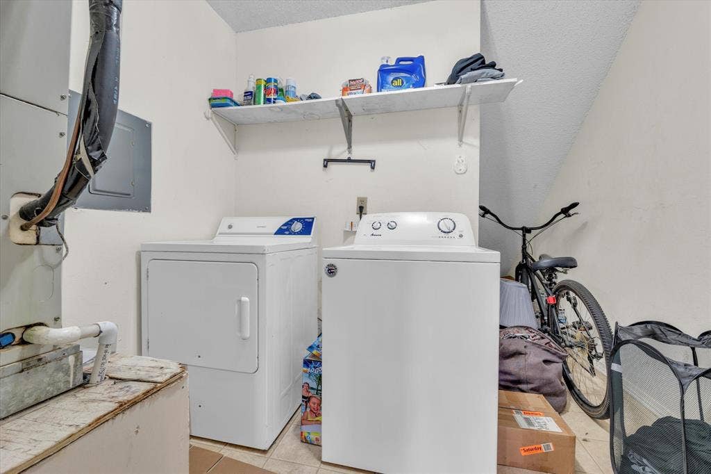 1349 S 11th Street, Waco, TX 76706 Laundry room featuring light tile patterned flooring, electric panel, separate washer and dryer, heating unit, and a textured ceiling
