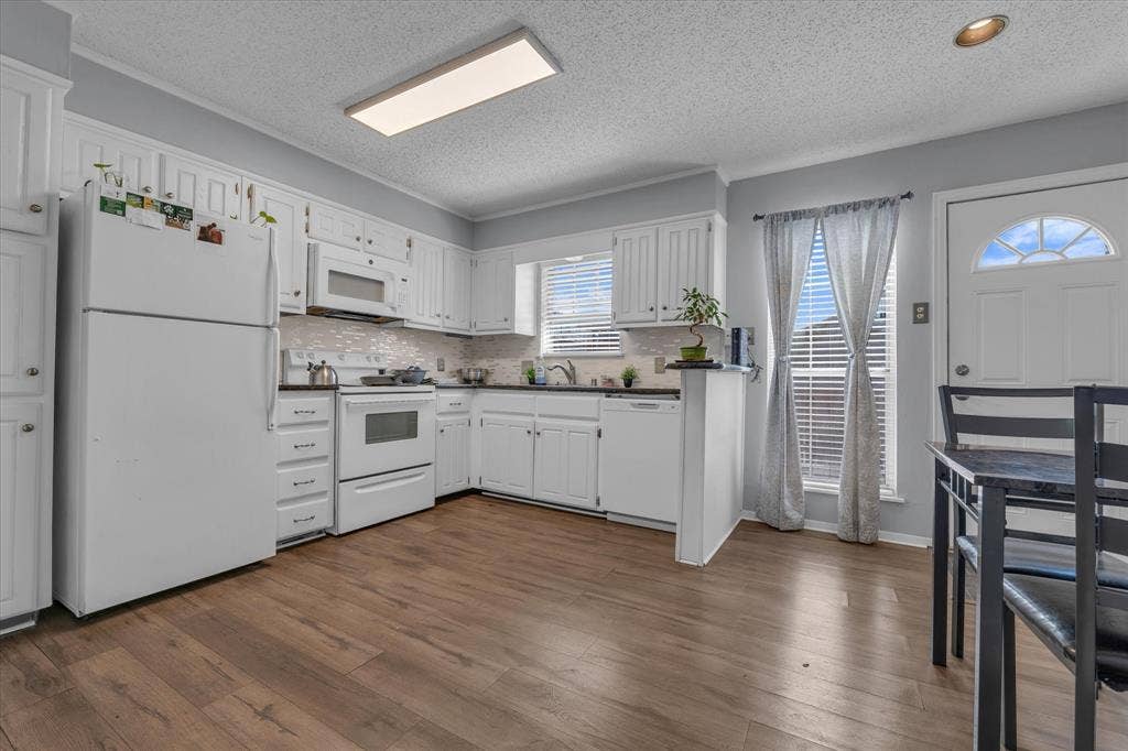 1349 S 11th Street, Waco, TX 76706 Kitchen with white appliances, white cabinetry, dark wood-type flooring, backsplash, and a textured ceiling