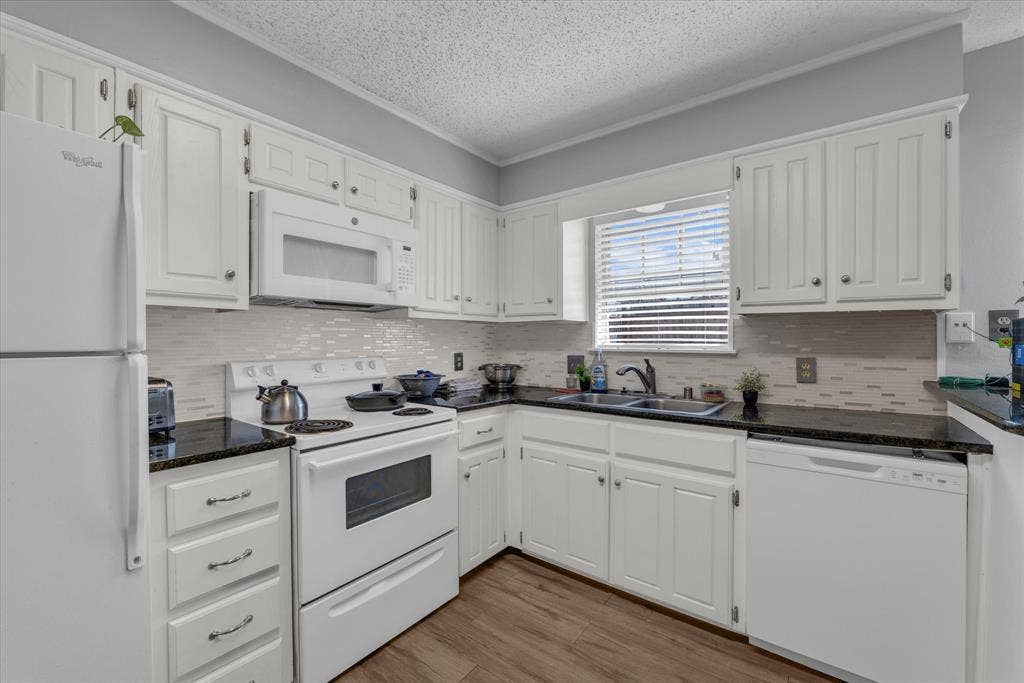 1349 S 11th Street, Waco, TX 76706 Kitchen featuring white appliances, white cabinetry, tasteful backsplash, light wood finished floors, and dark stone counters