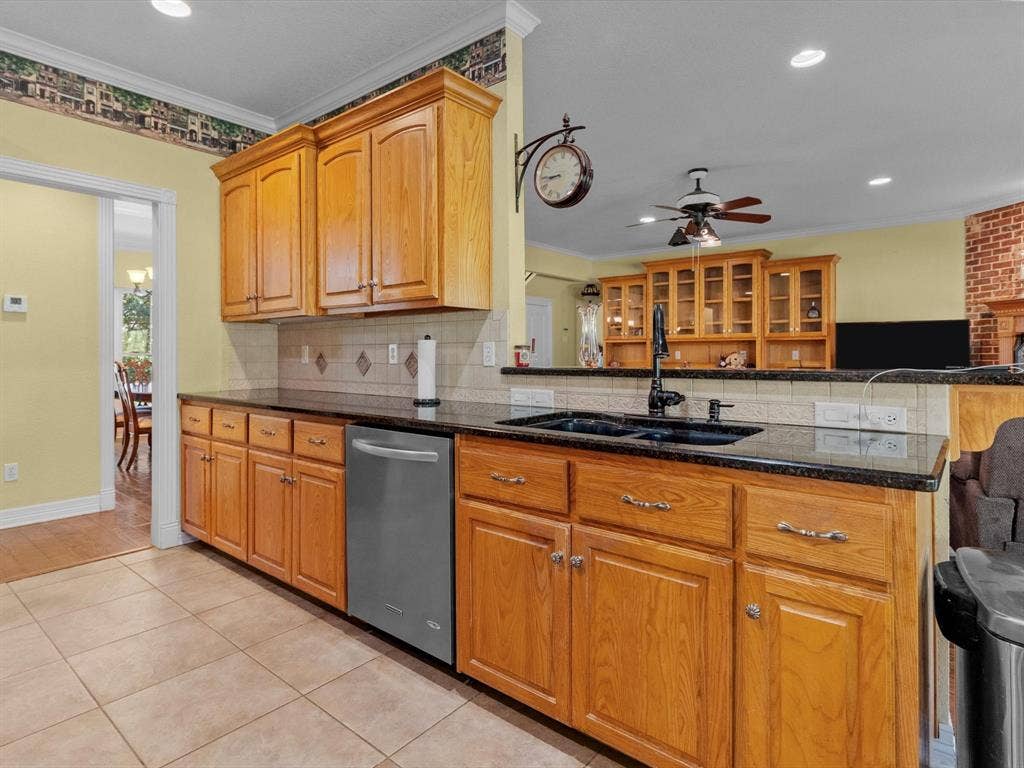 20941 Fm 16 W, Lindale, TX 75771 Kitchen with crown molding, tasteful backsplash, light tile patterned floors, dark stone counters, and stainless steel dishwasher