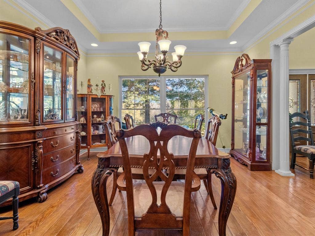 20941 Fm 16 W, Lindale, TX 75771 Dining area featuring decorative columns, a tray ceiling, light wood finished floors, ornamental molding, and a chandelier
