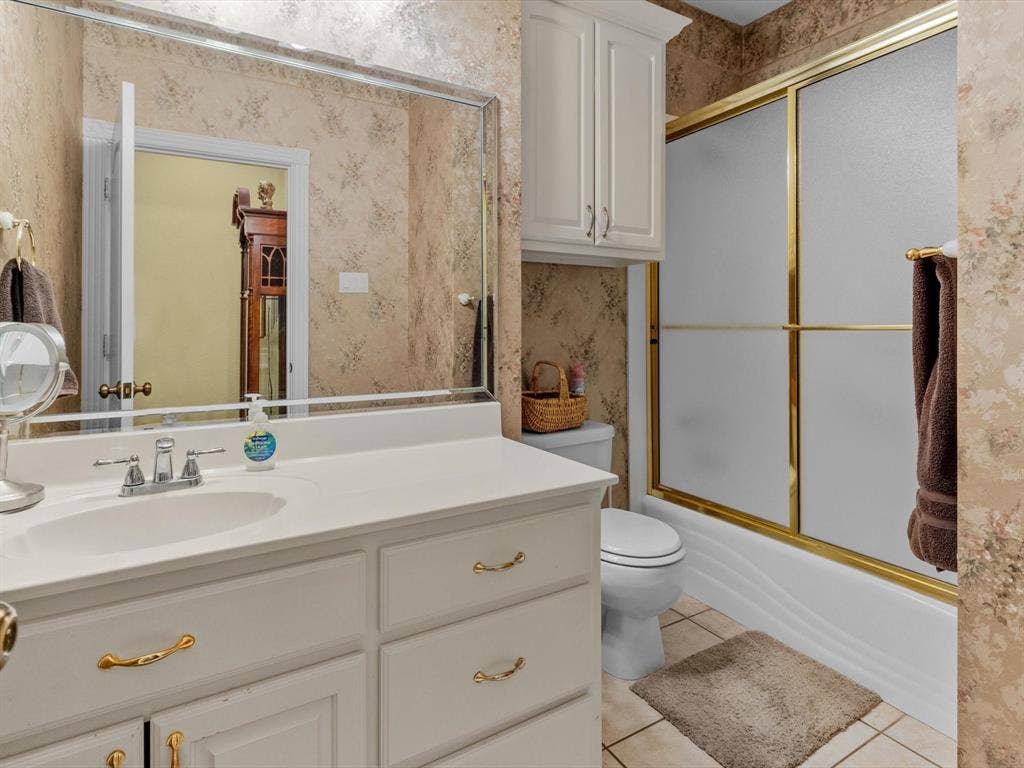 20941 Fm 16 W, Lindale, TX 75771 Full bathroom with light tile patterned floors, wallpapered walls, shower / bath combination with glass door, and vanity