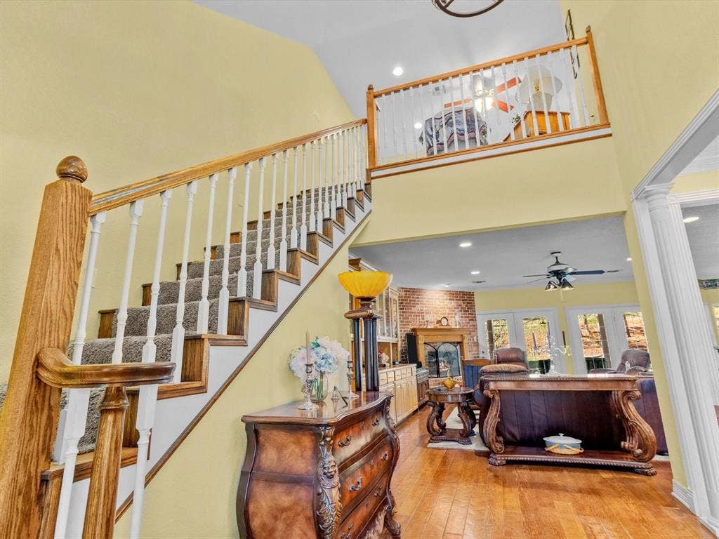 20941 Fm 16 W, Lindale, TX 75771 Staircase featuring a brick fireplace, recessed lighting, hardwood / wood-style floors, decorative columns, and a high ceiling