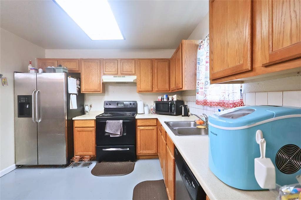 14186 Austin Street, Log Cabin, TX 75148 Kitchen featuring black appliances, light countertops, under cabinet range hood, concrete floors, and brown cabinets