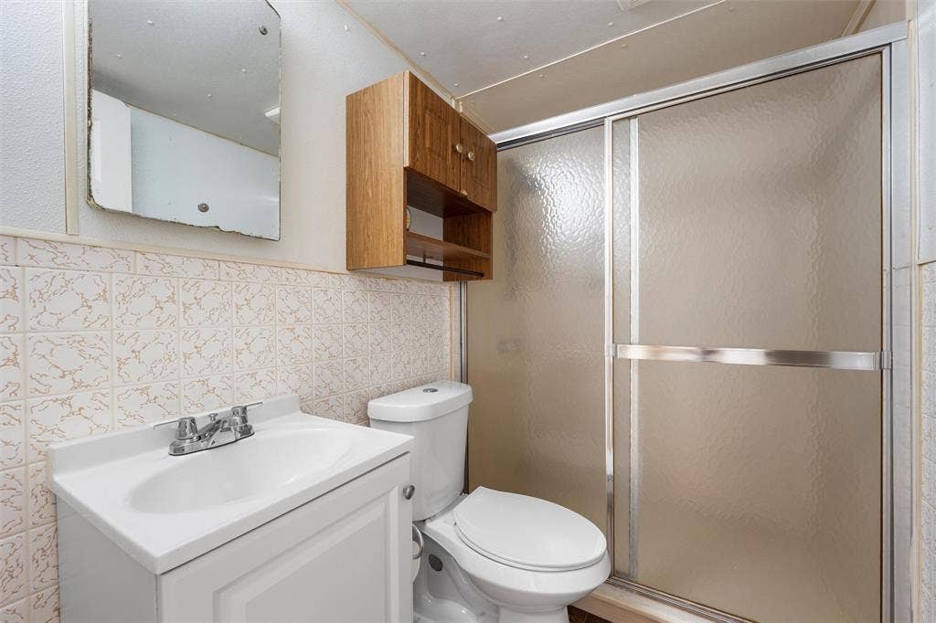 12145 Tree Lake Drive, Waco, TX 76708 Full bathroom with a stall shower, vanity, and tile walls