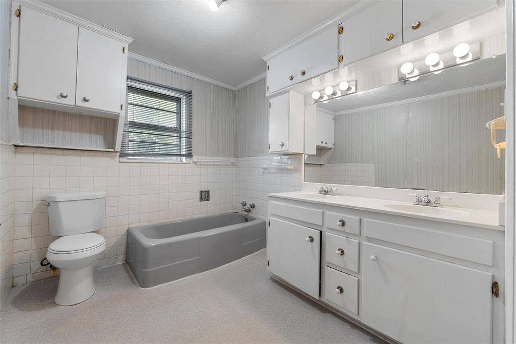 12145 Tree Lake Drive, Waco, TX 76708 Full bath featuring a bath, double vanity, crown molding, wallpapered walls, and tile walls