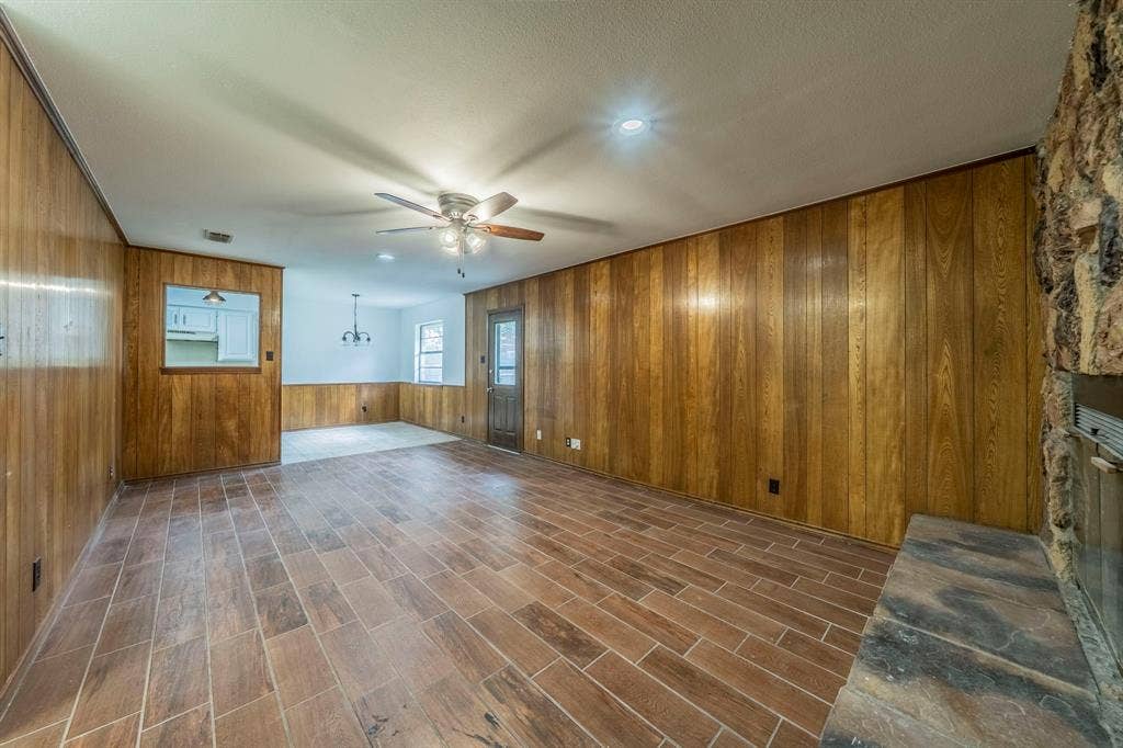 105 Briar Lane, Waxahachie, TX 75165 Unfurnished living room featuring wooden walls, ceiling fan, and dark wood finished floors