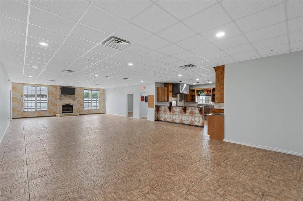 Unfurnished living room with healthy amount of natural light, a fireplace, a drop ceiling, and recessed lighting