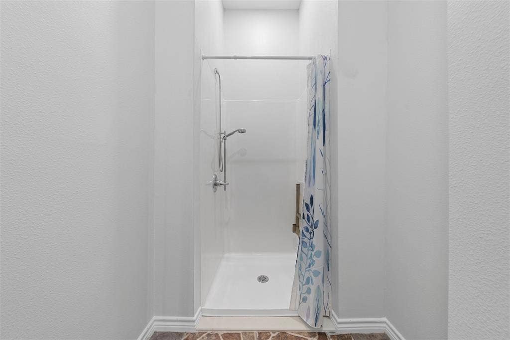 Bathroom with a shower stall and a textured wall